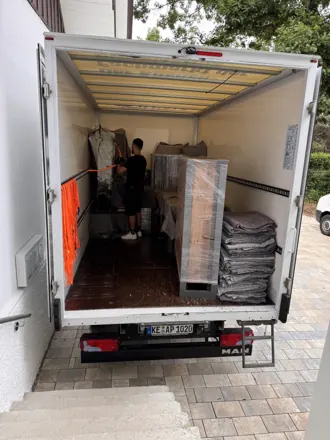 Mitarbeiter belädt den Umzugs-LKW, Möbel in Decken geschützt